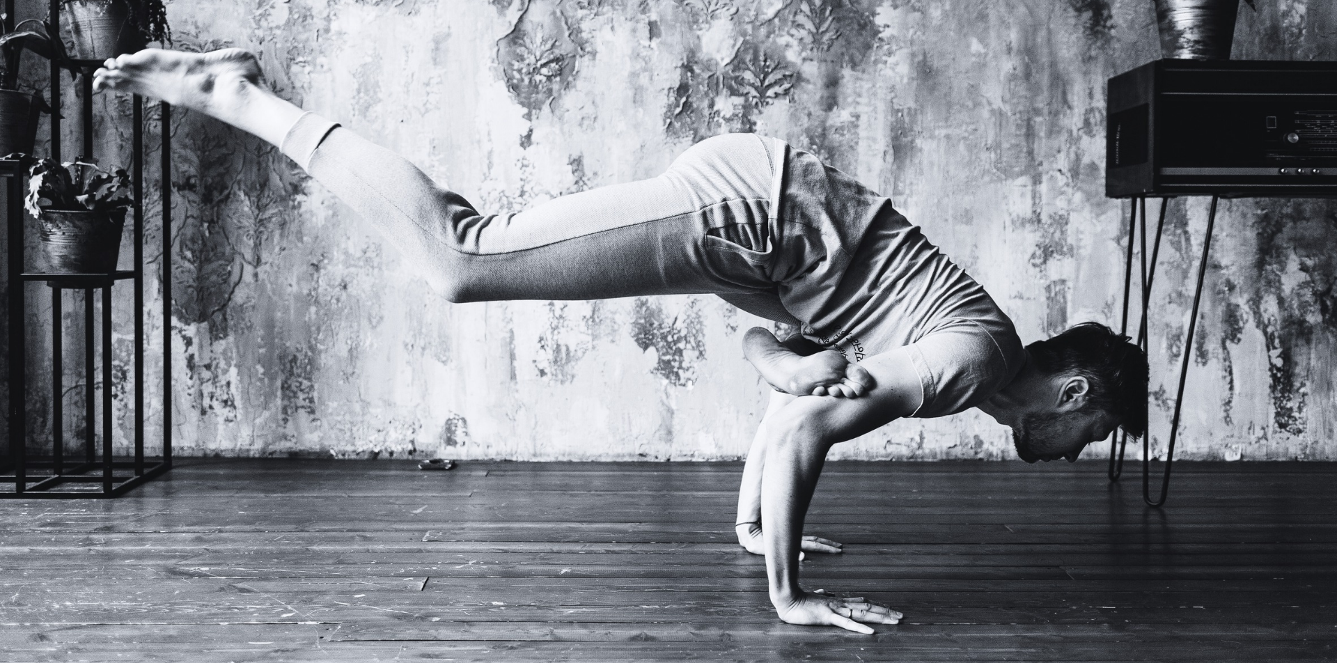 Man in a yoga arm balance with one leg in the air